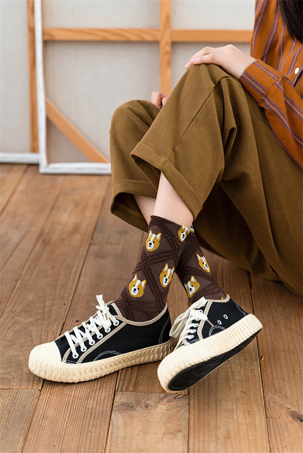 Person wearing brown socks with guitar design and black sneakers on a wooden floor.