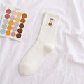 White sock with a fox design and a color swatch book on a white background