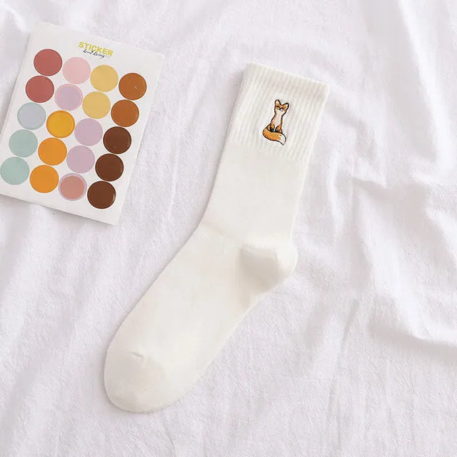 White sock with a fox design and a color swatch book on a white background