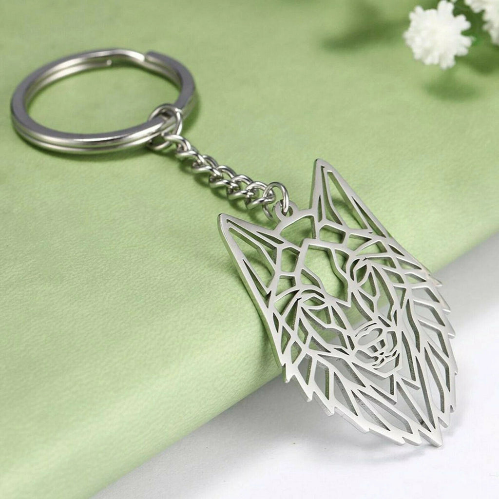 Silver geometric wolf head keychain on a light green fabric background