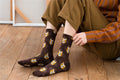 Person wearing brown socks with dog patterns on a wooden floor.